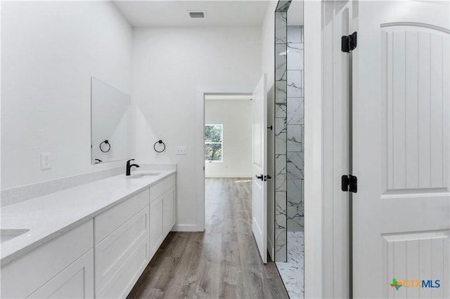 bathroom with a tile shower, vanity, and hardwood / wood-style flooring