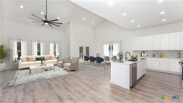 kitchen with sink, white cabinetry, tasteful backsplash, stainless steel dishwasher, and a kitchen island with sink