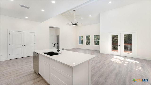 kitchen featuring sink, white cabinets, french doors, a center island with sink, and high vaulted ceiling