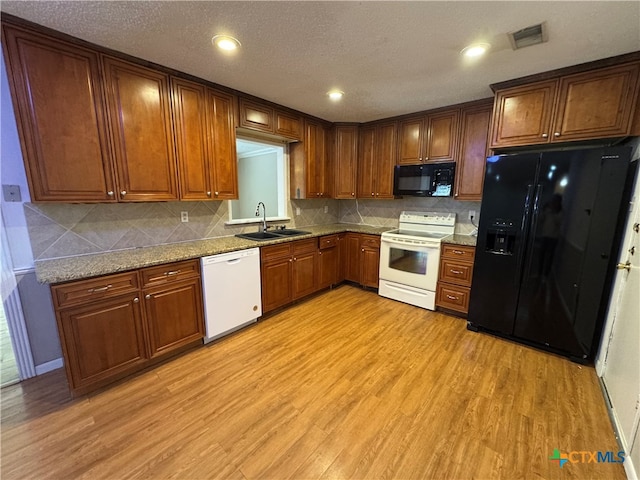 kitchen featuring black appliances, sink, light stone countertops, a textured ceiling, and light hardwood / wood-style floors