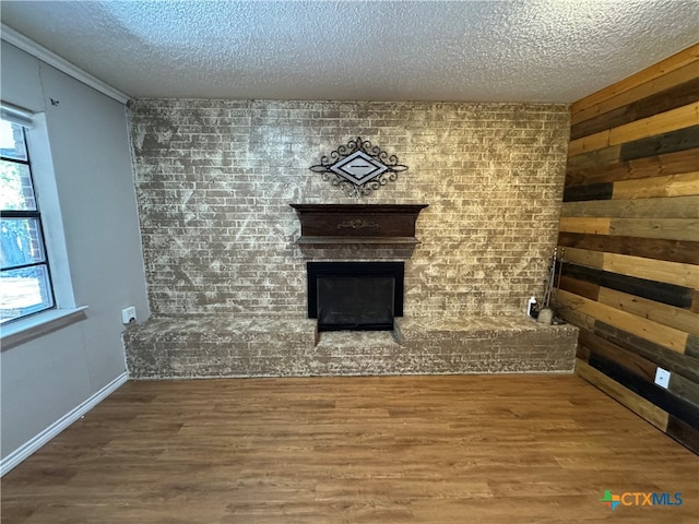 unfurnished living room featuring hardwood / wood-style flooring, crown molding, and a textured ceiling