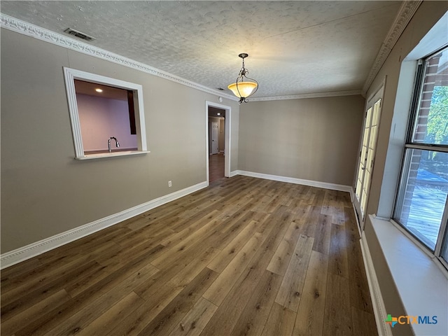 unfurnished room featuring hardwood / wood-style floors, ornamental molding, and a textured ceiling