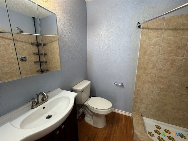 bathroom with a tile shower, sink, hardwood / wood-style floors, and toilet