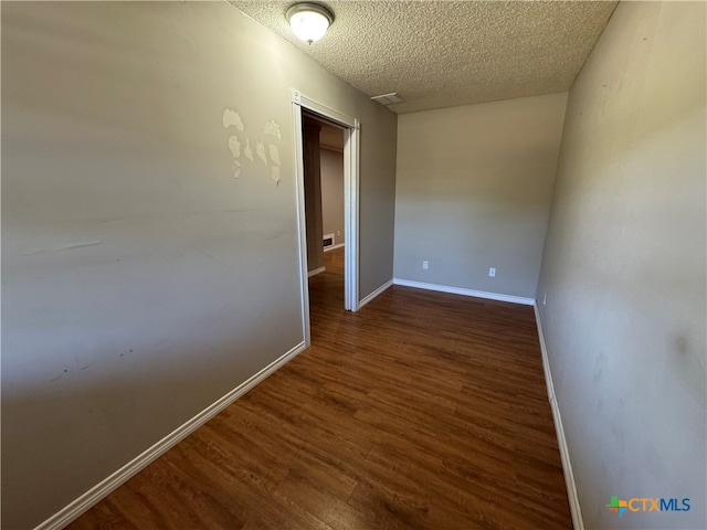 corridor with a textured ceiling and dark wood-type flooring