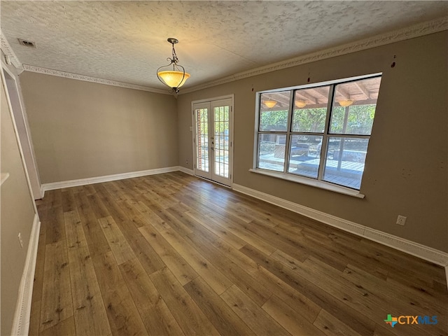 unfurnished room with french doors, a textured ceiling, crown molding, and hardwood / wood-style floors