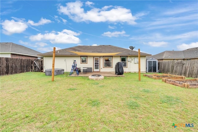 rear view of house with an outdoor fire pit, a fenced backyard, a storage unit, a lawn, and a garden