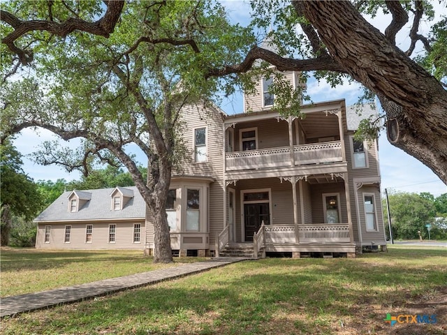 view of front of home featuring covered porch, a front yard, and a balcony
