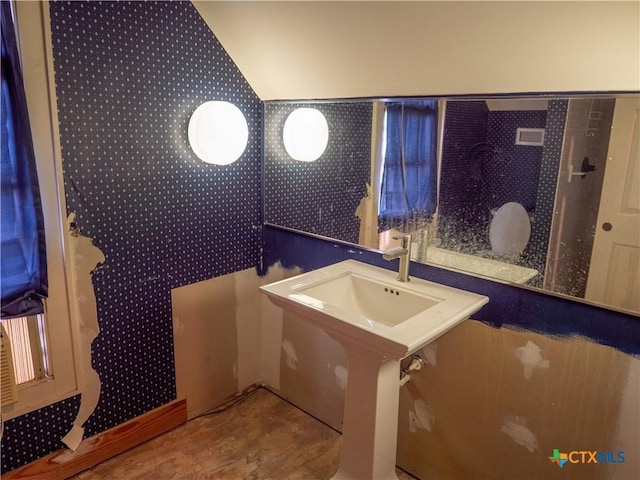 bathroom featuring vaulted ceiling and wallpapered walls
