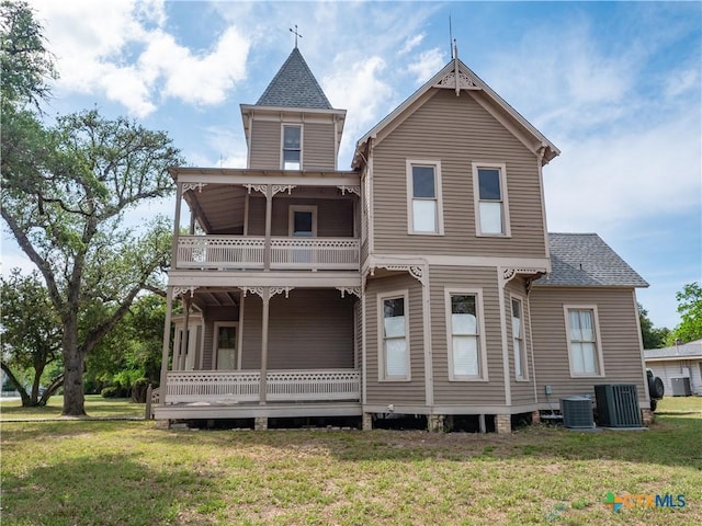 rear view of house featuring cooling unit, roof with shingles, a yard, and a balcony