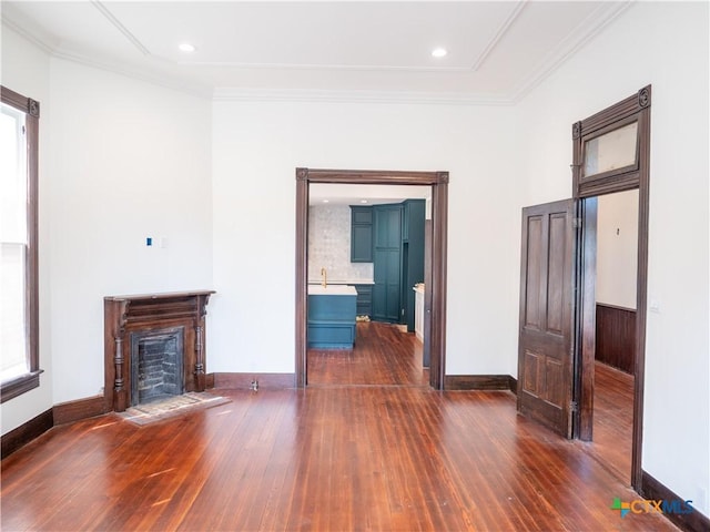 unfurnished living room featuring crown molding, a sink, a fireplace, baseboards, and dark wood-style flooring