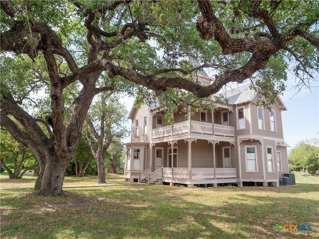 view of front of home featuring cooling unit, a front yard, and a balcony