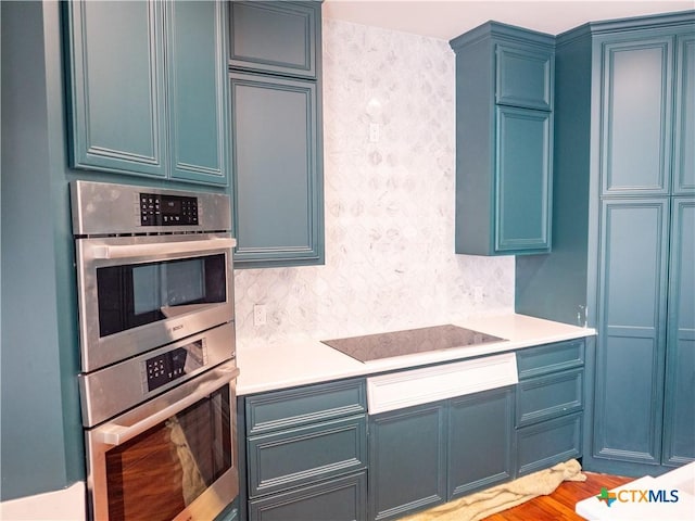 kitchen with light countertops, black electric cooktop, blue cabinets, and double oven