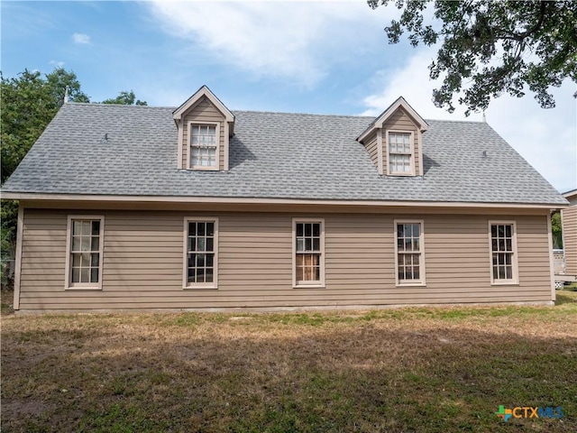 back of property with a lawn and roof with shingles