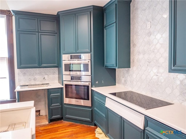 kitchen featuring black electric cooktop, plenty of natural light, decorative backsplash, and double oven