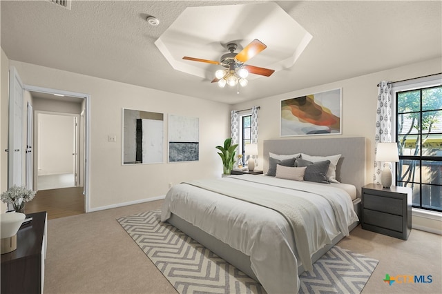 carpeted bedroom featuring ceiling fan, multiple windows, and a textured ceiling