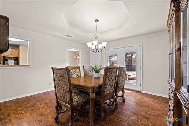 dining room with a raised ceiling, french doors, a chandelier, and dark hardwood / wood-style floors