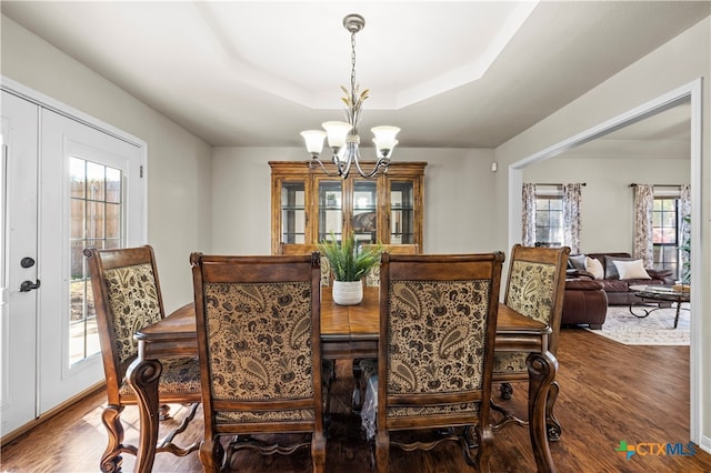 dining area with french doors, a raised ceiling, a chandelier, and hardwood / wood-style floors