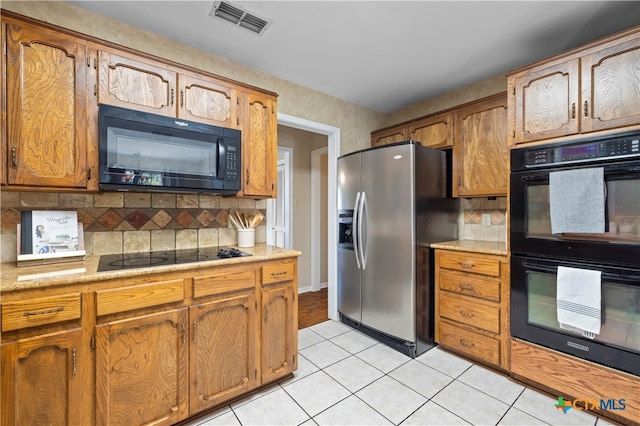 kitchen with backsplash, light tile patterned floors, and black appliances