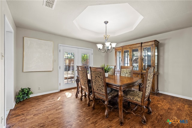 dining room with french doors, an inviting chandelier, a tray ceiling, and dark hardwood / wood-style floors