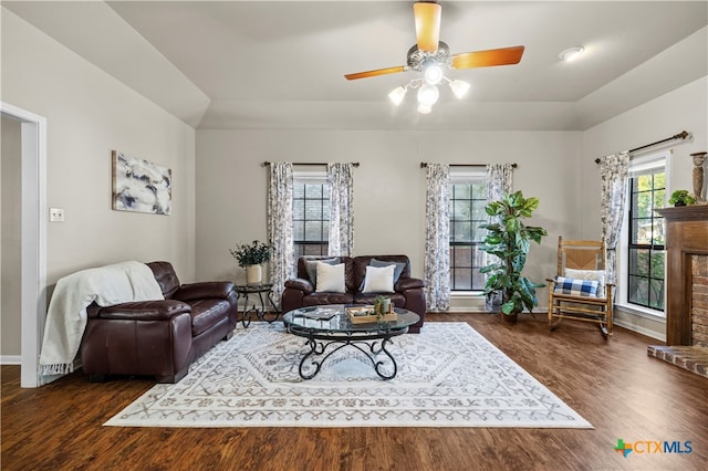 living room featuring a brick fireplace, ceiling fan, a healthy amount of sunlight, and dark hardwood / wood-style floors