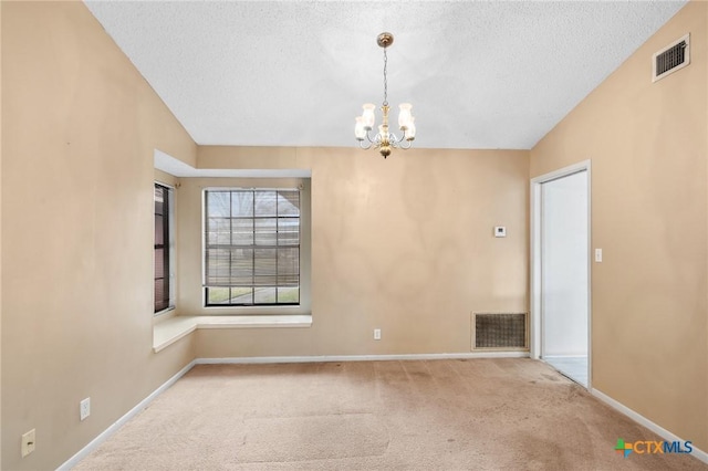 spare room with carpet, a textured ceiling, and a chandelier