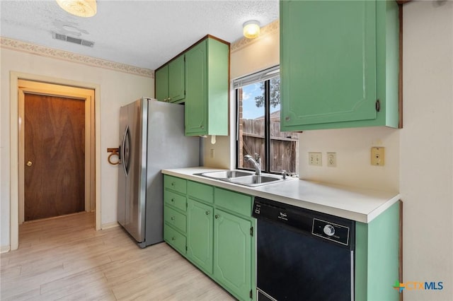 kitchen featuring sink, light hardwood / wood-style flooring, stainless steel refrigerator, black dishwasher, and green cabinetry