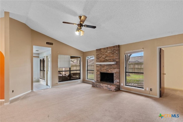 unfurnished living room featuring ceiling fan, light colored carpet, a fireplace, and vaulted ceiling