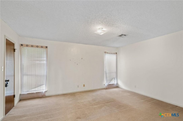 carpeted empty room featuring a textured ceiling