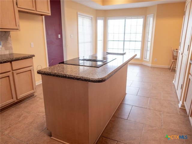 kitchen featuring a kitchen island, dark stone counters, light tile patterned flooring, black electric stovetop, and tasteful backsplash