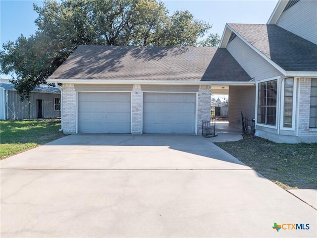 view of front of property featuring a garage, brick siding, roof with shingles, and concrete driveway