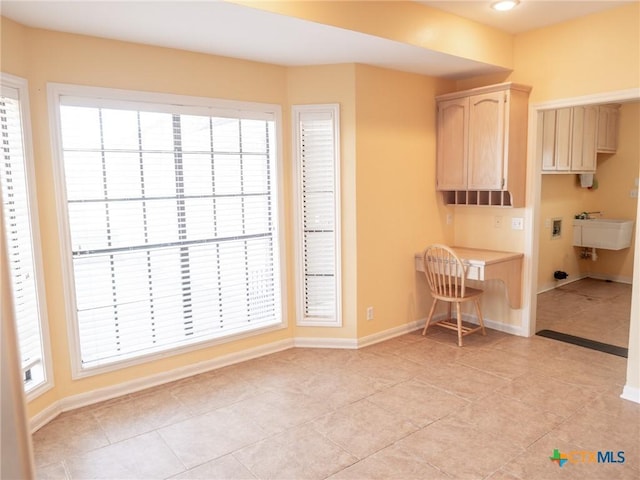 unfurnished dining area featuring light tile patterned floors, baseboards, and a sink