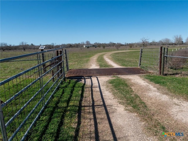 exterior space featuring a gate, a rural view, a lawn, and fence