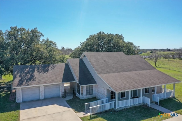 view of front facade featuring driveway, stone siding, covered porch, a front yard, and a garage