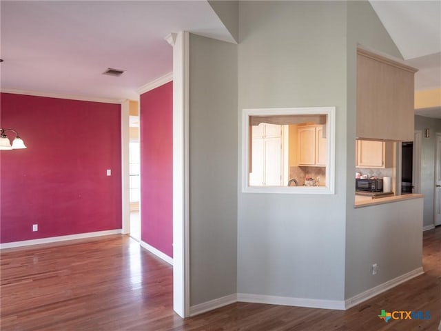 interior space featuring crown molding, wood finished floors, visible vents, and baseboards