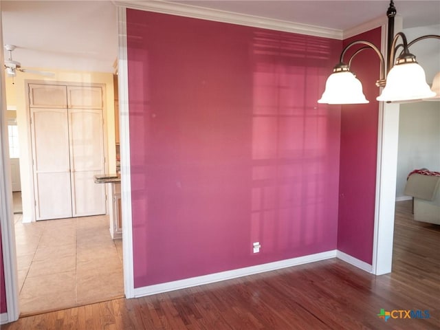 unfurnished dining area featuring ceiling fan, baseboards, wood finished floors, and crown molding