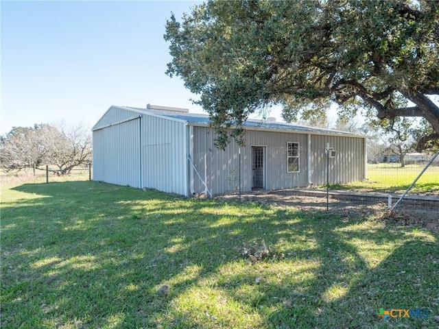 exterior space with a lawn, fence, an outdoor structure, and a pole building