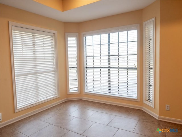 tiled spare room featuring baseboards and a wealth of natural light