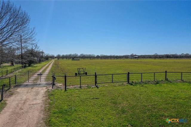 view of yard with a gate, a rural view, fence, and driveway