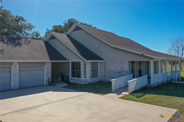 view of front of house with a front yard, a shingled roof, concrete driveway, a garage, and brick siding