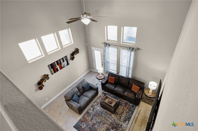 living room featuring ceiling fan, light tile patterned floors, and a high ceiling