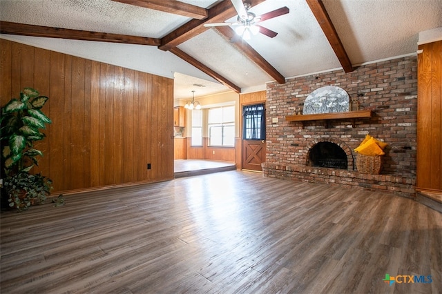 unfurnished living room with a brick fireplace, wooden walls, a textured ceiling, and dark hardwood / wood-style flooring