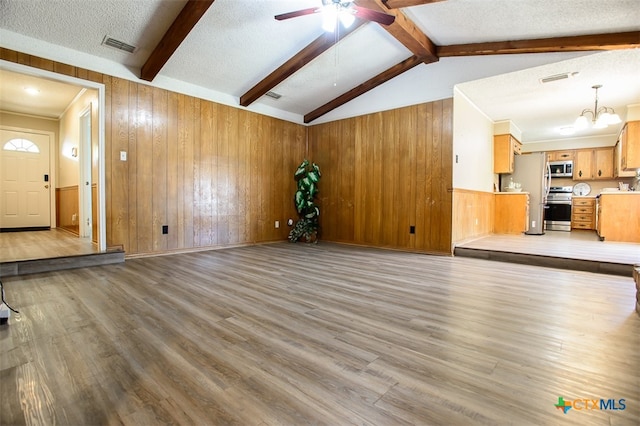 unfurnished living room with a textured ceiling, light wood-type flooring, and vaulted ceiling with beams