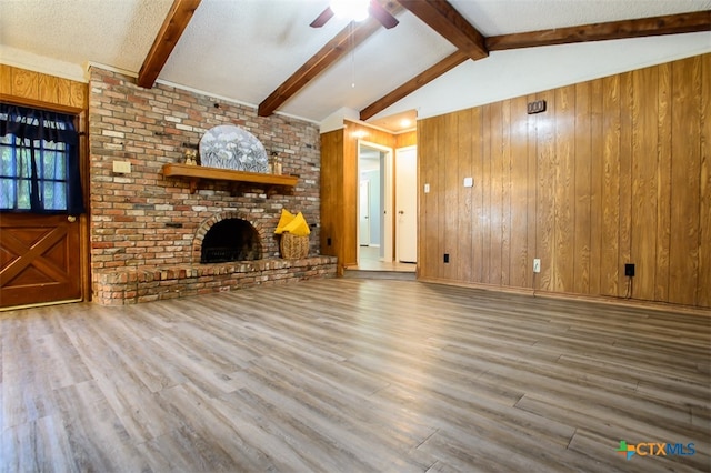 unfurnished living room with wood walls, wood-type flooring, and a brick fireplace