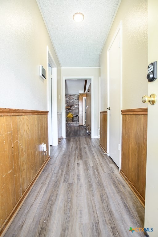 hallway featuring hardwood / wood-style floors, wood walls, and a textured ceiling