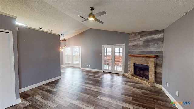 unfurnished living room with ceiling fan with notable chandelier, dark wood-type flooring, a textured ceiling, and french doors