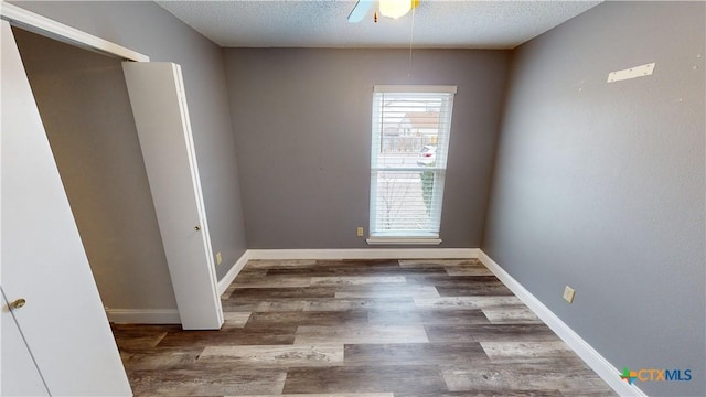 empty room with ceiling fan, a textured ceiling, and dark hardwood / wood-style flooring