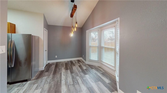 unfurnished dining area with vaulted ceiling and wood-type flooring