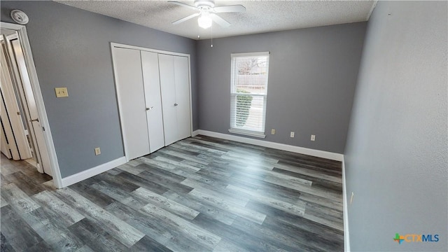 unfurnished bedroom featuring a textured ceiling, ceiling fan, a closet, and dark hardwood / wood-style floors