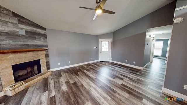 unfurnished living room with a brick fireplace, a wealth of natural light, lofted ceiling, and hardwood / wood-style flooring