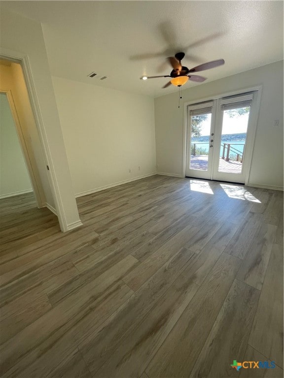 empty room featuring french doors, dark wood-type flooring, and ceiling fan